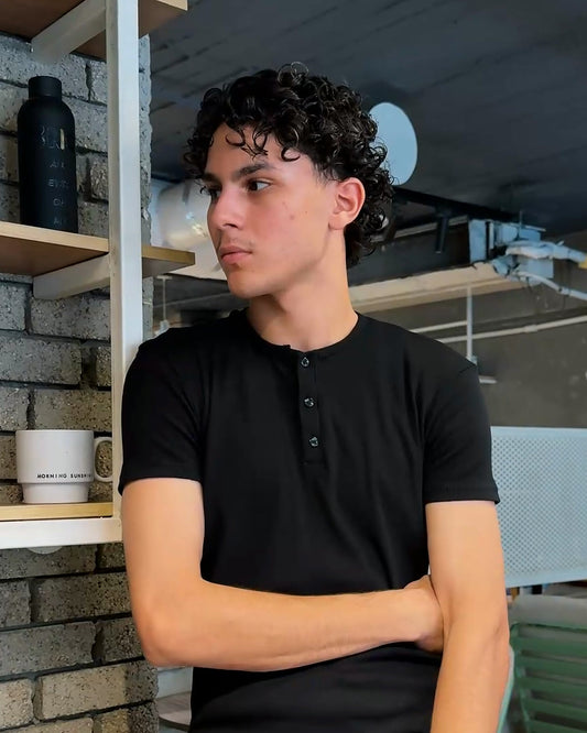AURRA Henley in Black — ribbed cotton, three-button placket, worn at a Cairo cafe